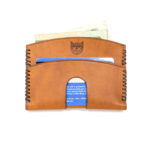 Brown leather card holder with cash and credit cards inside, Crosstitch cat emblem